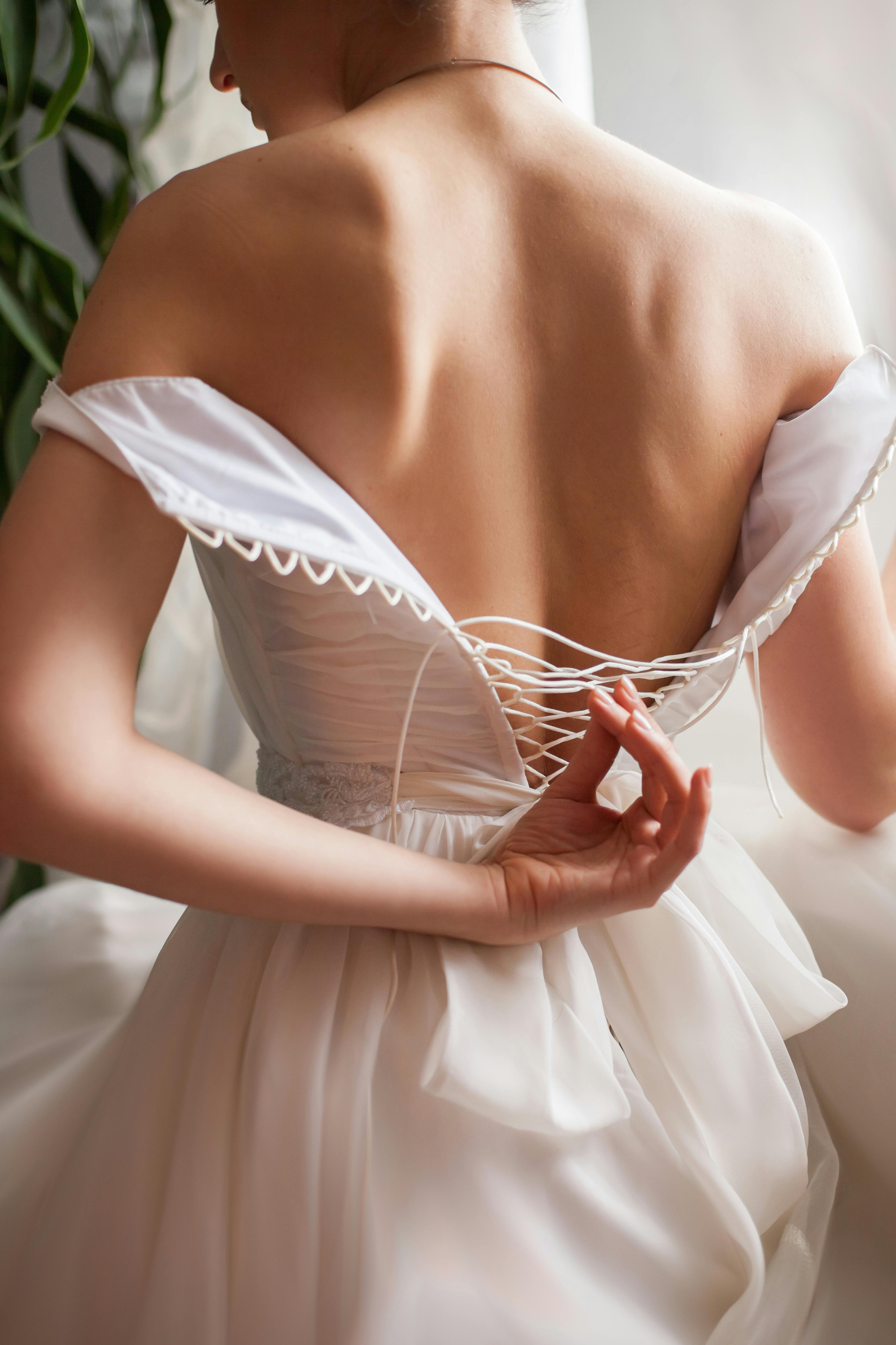 Close-up of a bride adjusting her wedding dress, showcasing elegance and style.