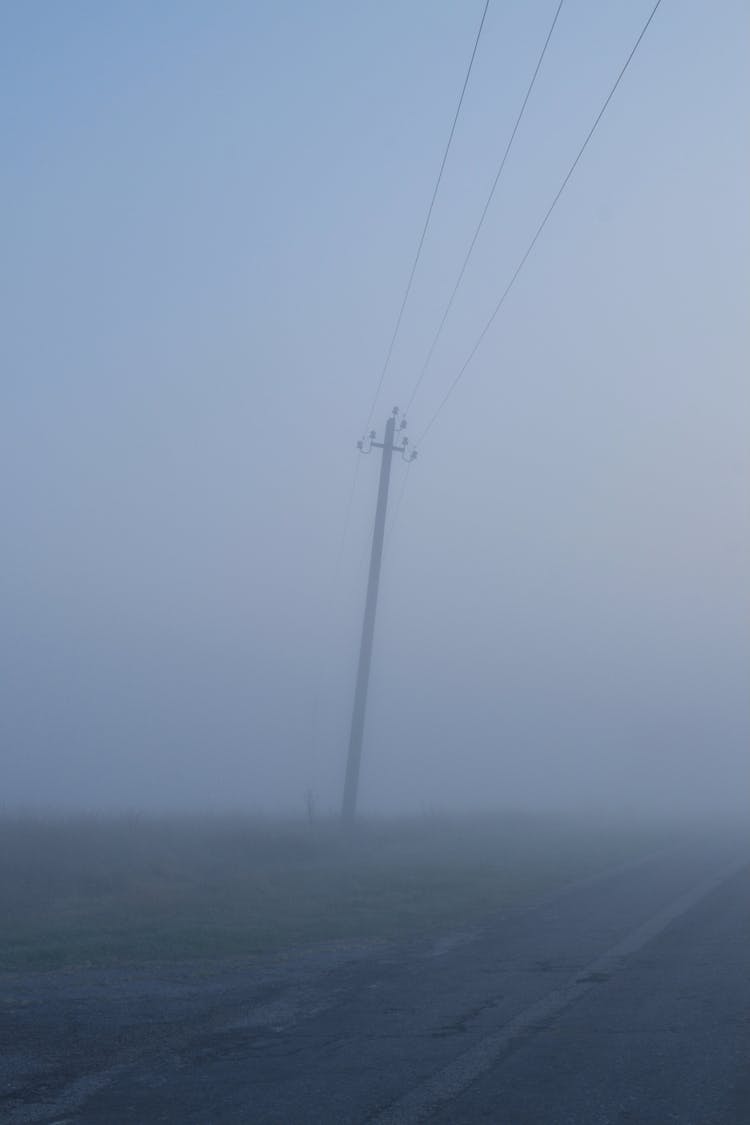 Tilted Pylon By A Road In A Fog 