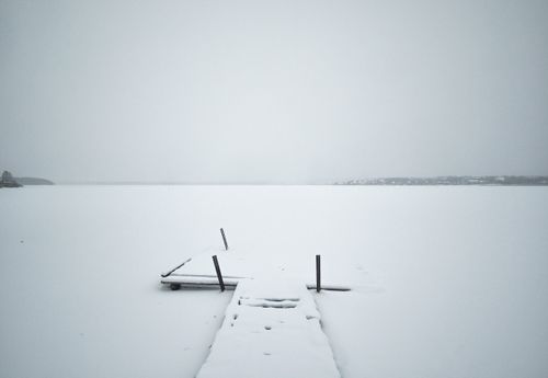 Free Minimalistic winter scene of a snow-covered pier on a frozen lake. Stock Photo
