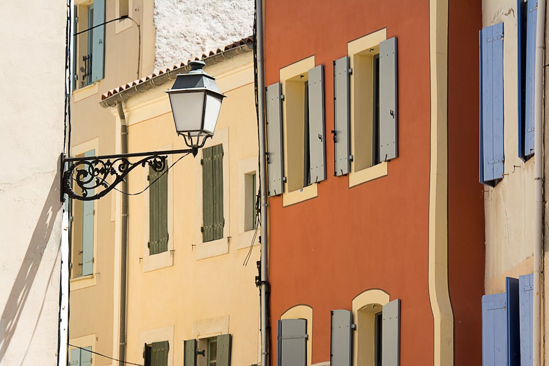 Hanging Street Lamp against Narrow Townhouses · Free Stock Photo