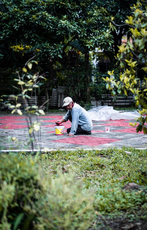 Free An adult man painting intricate designs on an outdoor pavement in Bandung, Indonesia. Stock Photo