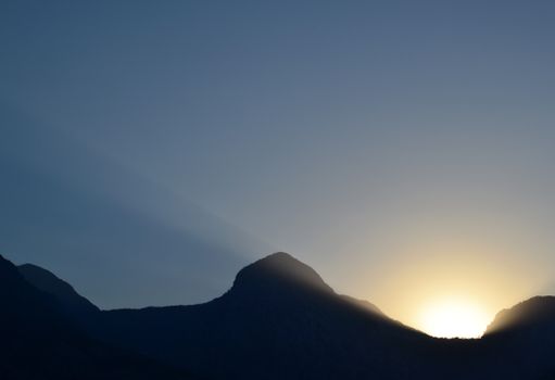 Beautiful silhouette of mountain peaks against a clear sky during sunrise, showcasing natural serenity.
