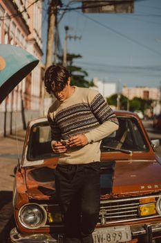 Young Man with Short Wavy Hair Standing Before Old Vintage Car