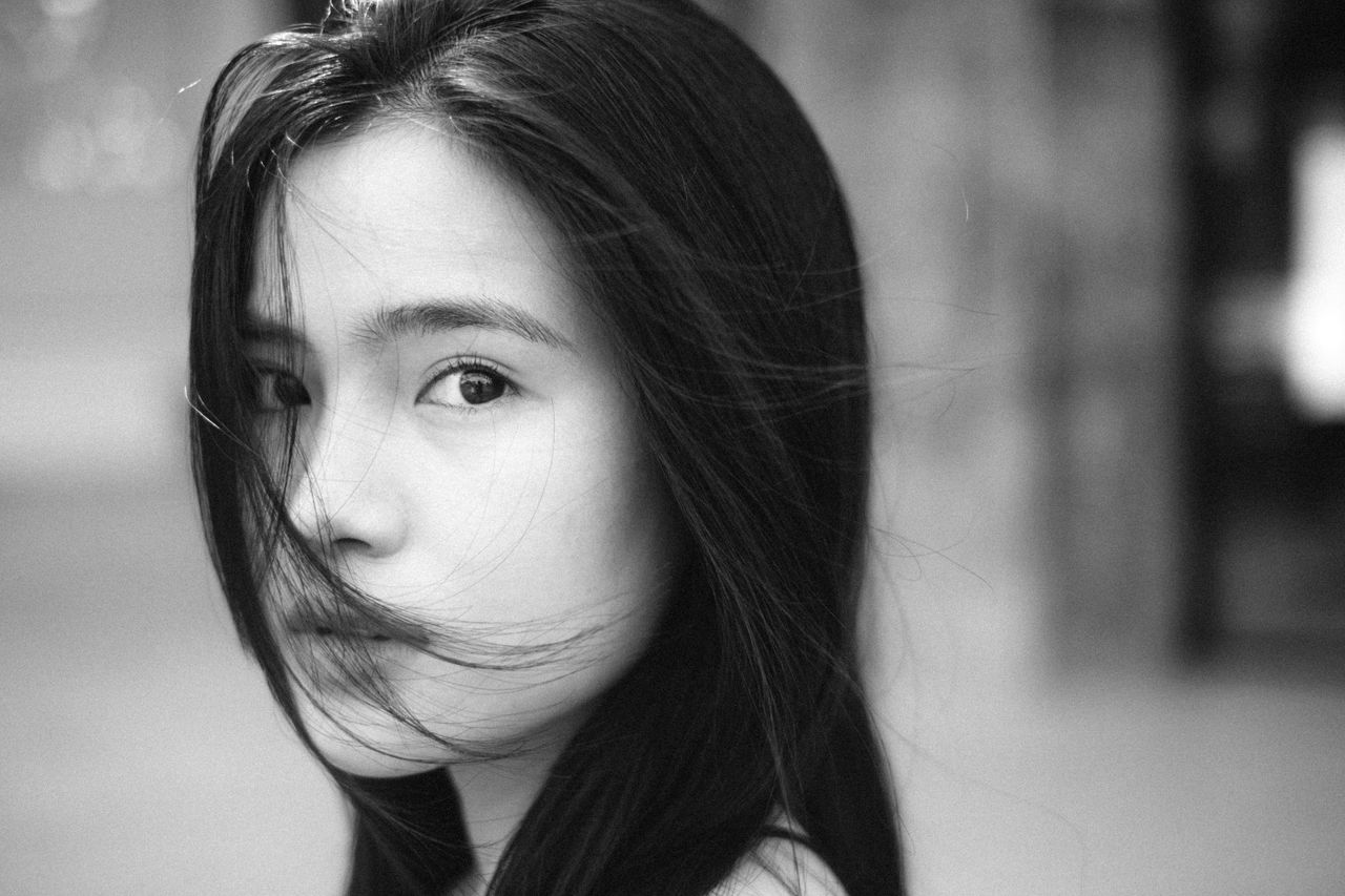 a captivating grayscale close up portrait of a young woman with black