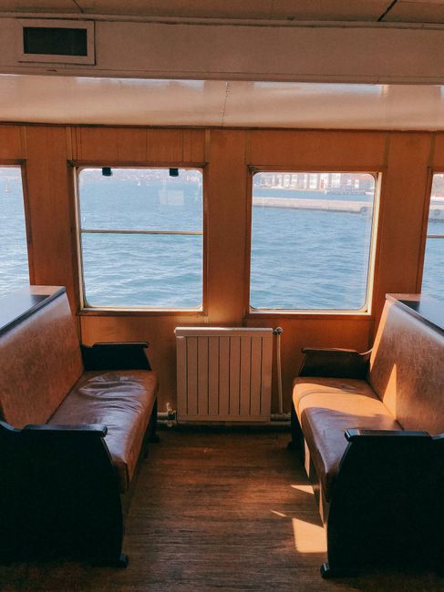 A serene view inside an empty boat cabin featuring wooden seats and ocean view through large windows.