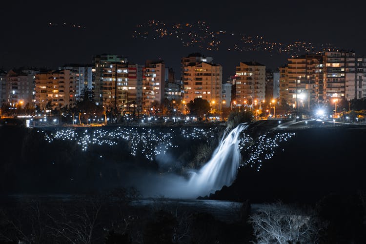 A Waterfall Near A City At Night