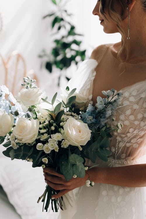 Woman in White Dress Holding White Rose Bouquet