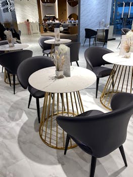A stylish cafe interior featuring marble tables with gold accents and modern chairs.