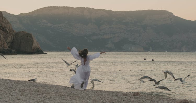 Woman In Dress Running On Beach