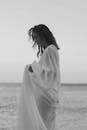 优雅的女人穿着飘逸的连衣裙，眺望大海，散发着宁静的气息