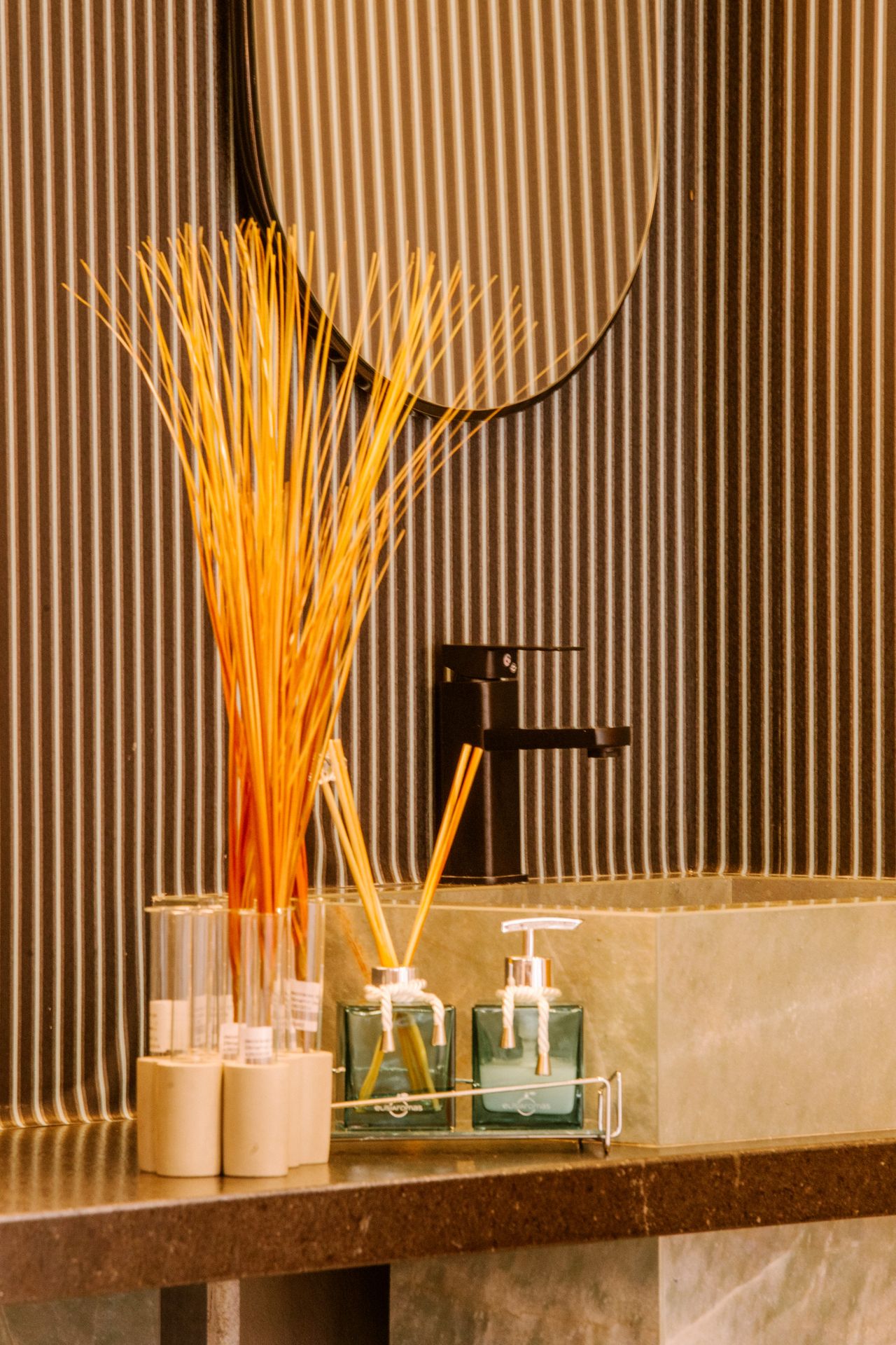 Styled bathroom counter with a glass soap dispenser beside a reed diffuser