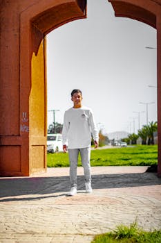 Adult male in a white sweater walking outdoors through an archway in Chillán Viejo, Chile.