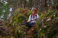 A Woman Sitting on Brown and Green Grass Holding a Stick