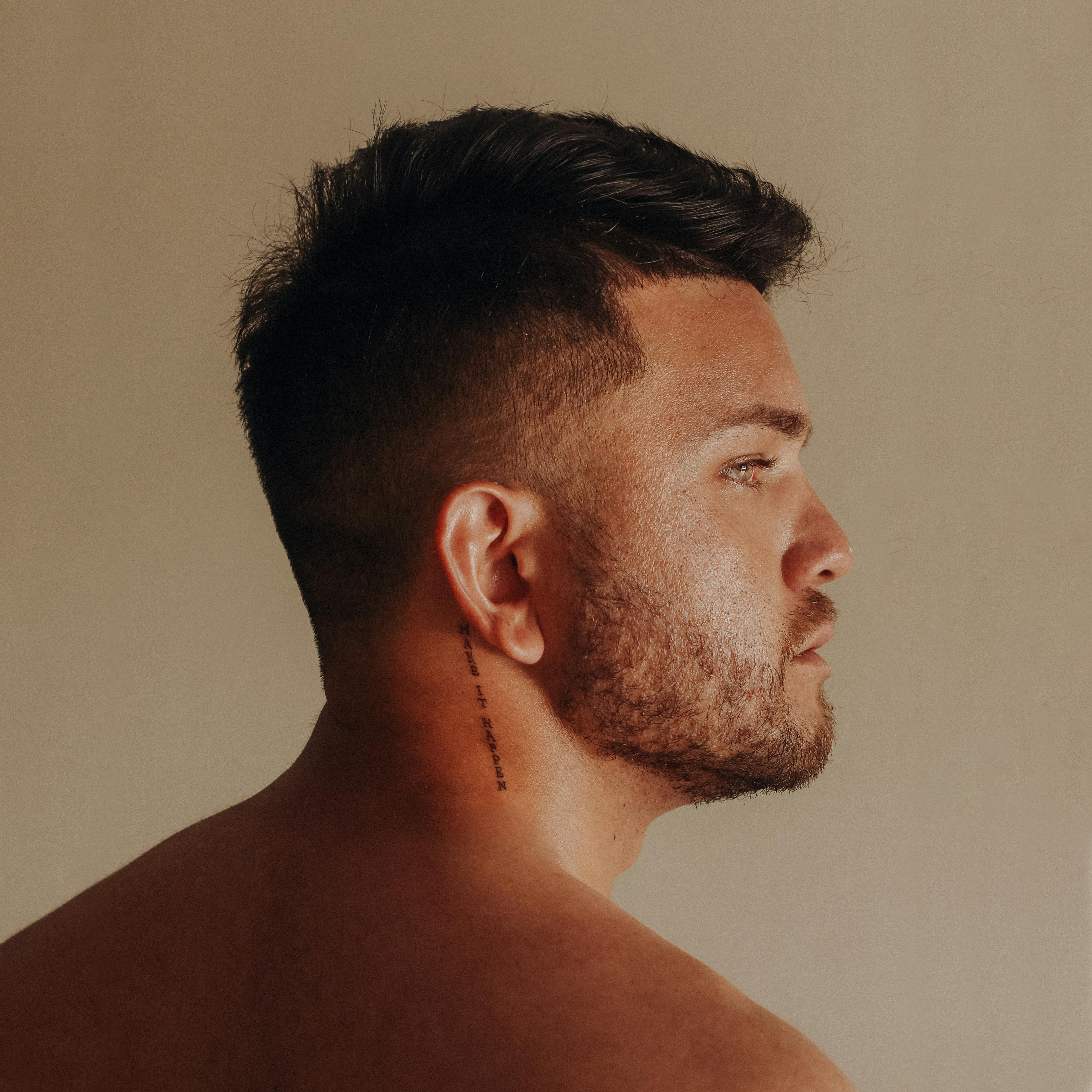 profile of a man with tattoo behind ear