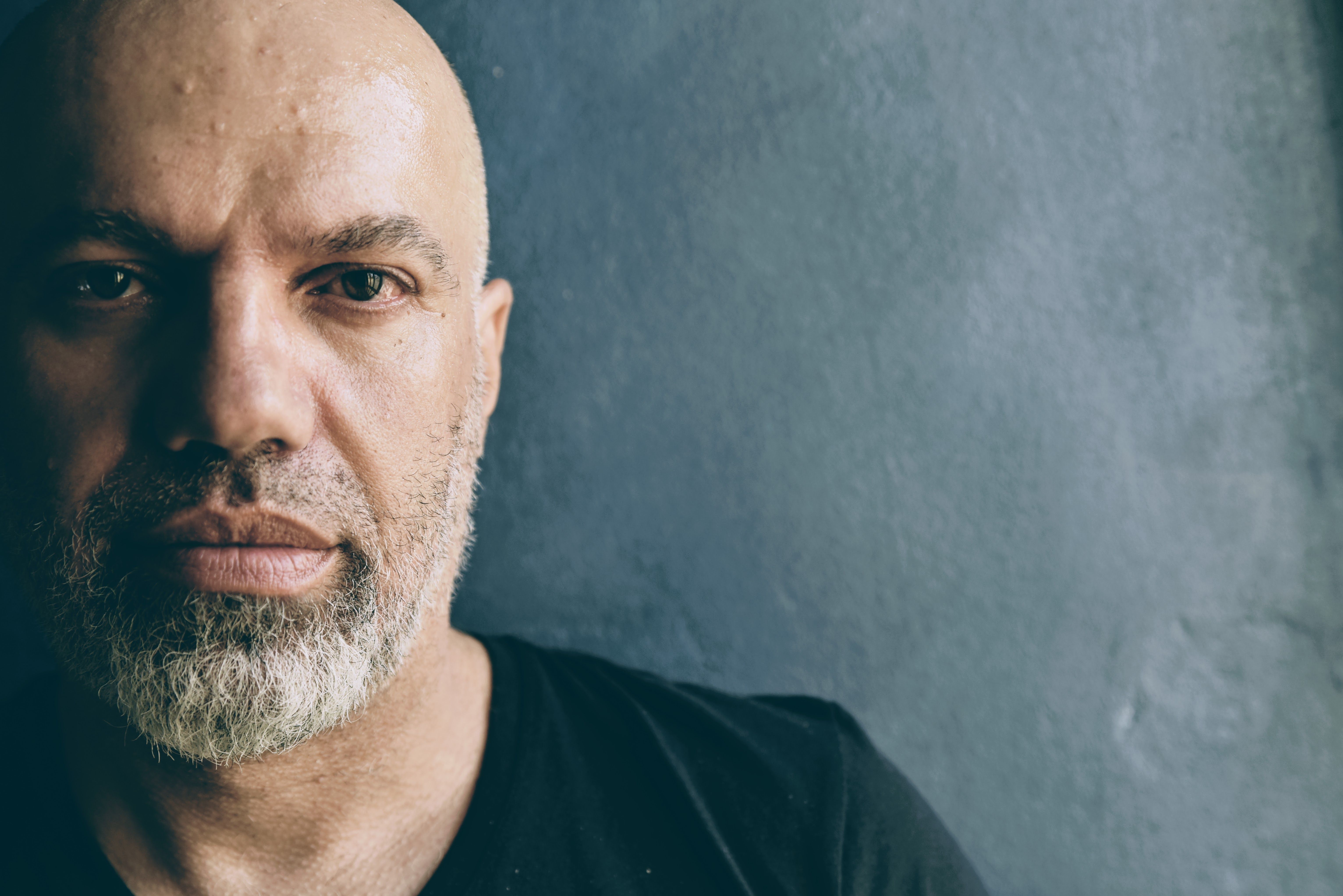 Moody close-up portrait of a bald man with a beard in dramatic light
