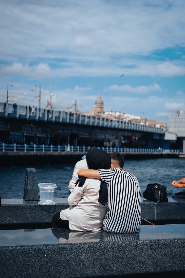 A Couple Sitting By A Sea