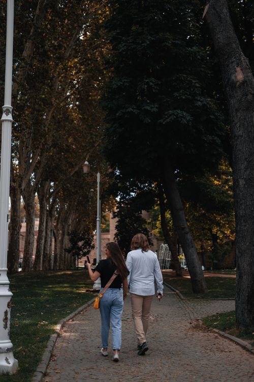 Free A couple walking hand-in-hand in an Istanbul park during autumn, captured in a vertical shot. Stock Photo