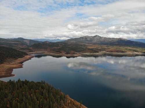 Aerial Photography of Calm Lake Surrounded by Mountains under the Cloudy Sky