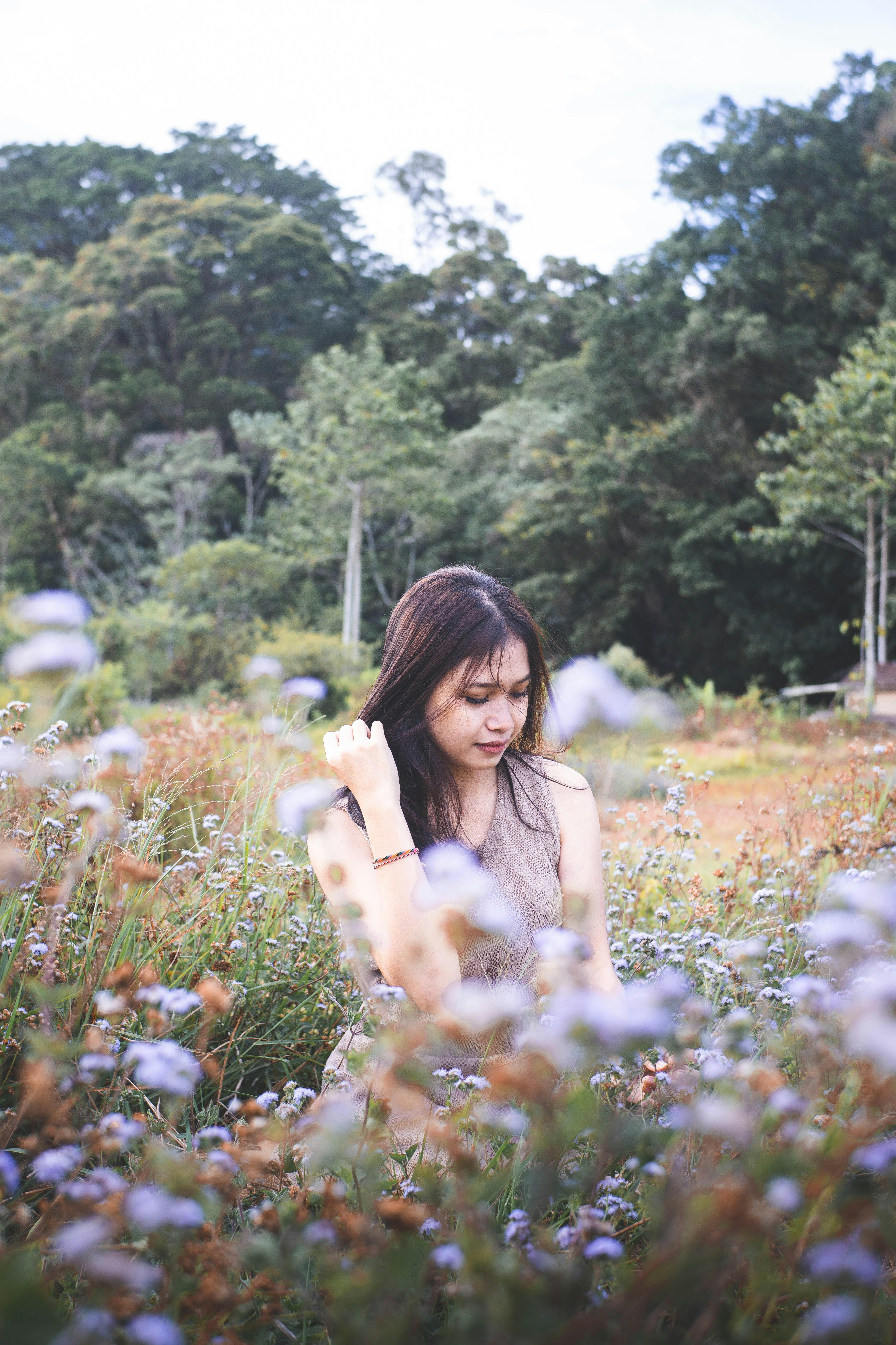 A woman enjoying a tranquil moment in a lush, colorful field in Bali, surrounded by nature.