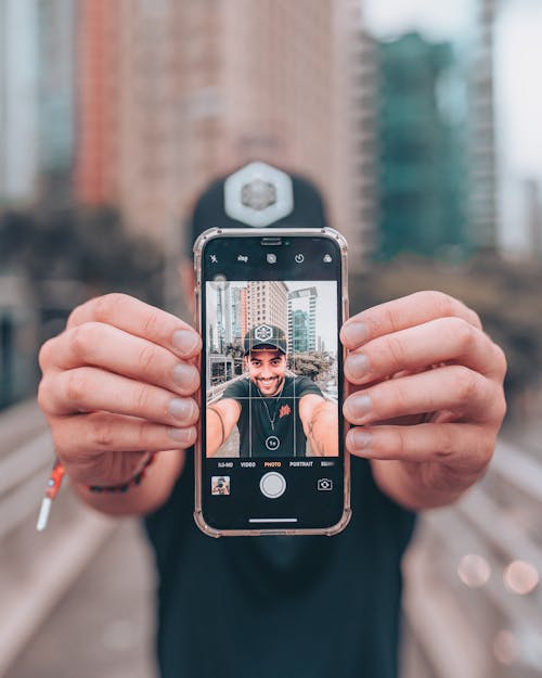 Close-Up Shot of a Man Holding a Cellphone while Taking Photo of Himself