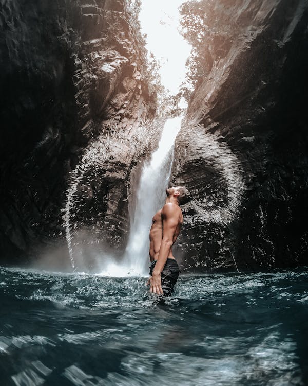 A Man Standing by a Waterfall