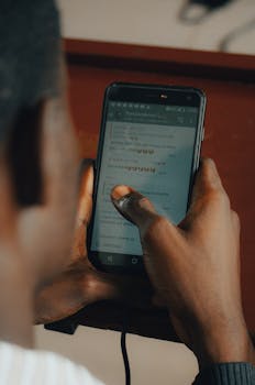 Person texting on a smartphone indoors with focus on hands and screen.