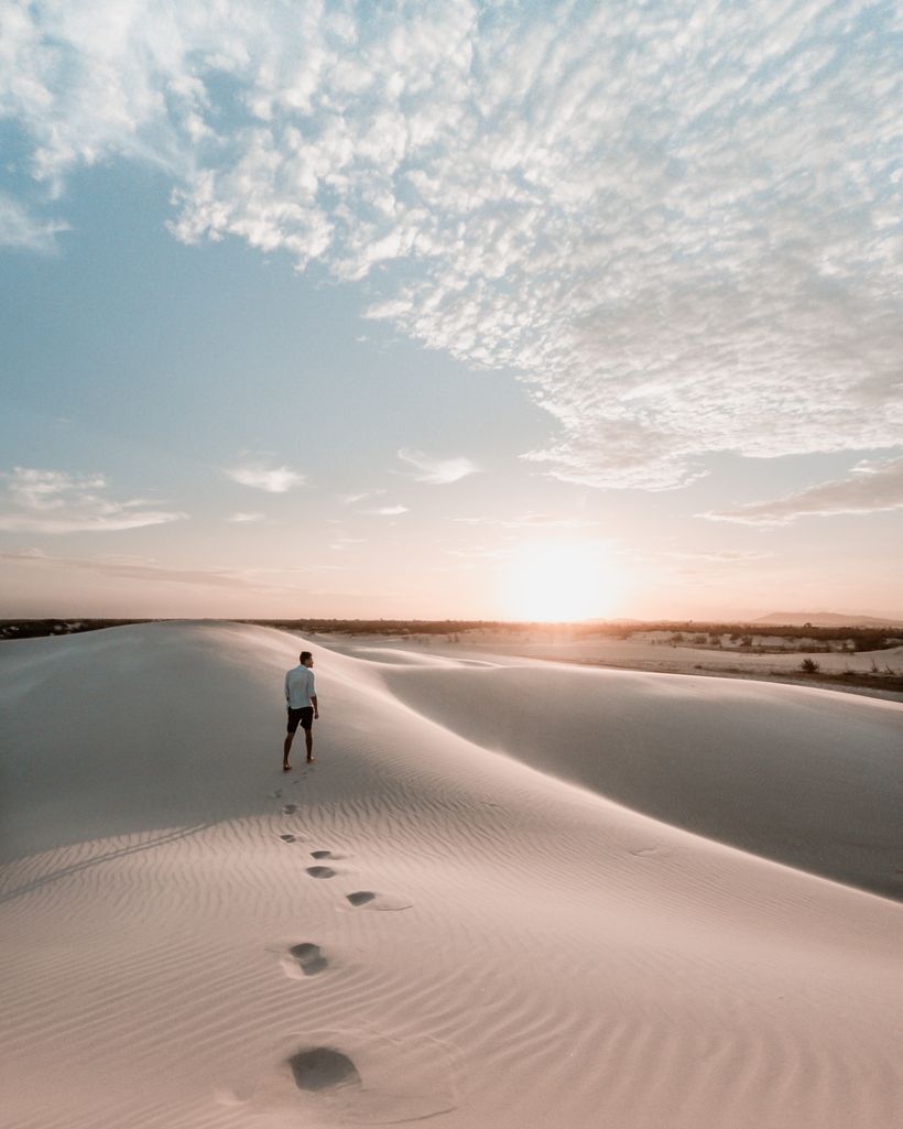 A lone walker crossing pale sand dunes at sunset — photo by Rodrigo Pederzini on Pexels