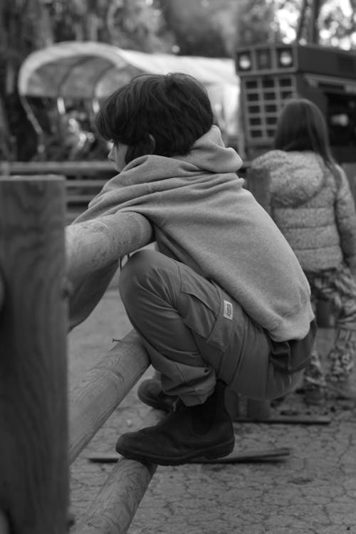 Free Grayscale Photo of a Kid Holding on a Wooden Railing Stock Photo
