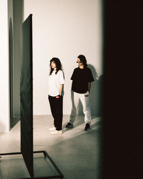 Free Two fashionable women in contrasting outfits pose in an artistic indoor setting. Stock Photo
