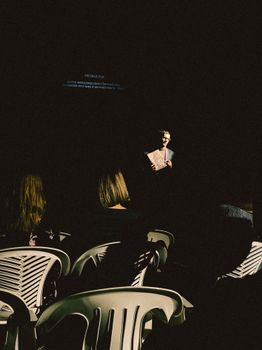 A gripping stage performance with a spotlight on the presenter in a dimly lit theater.