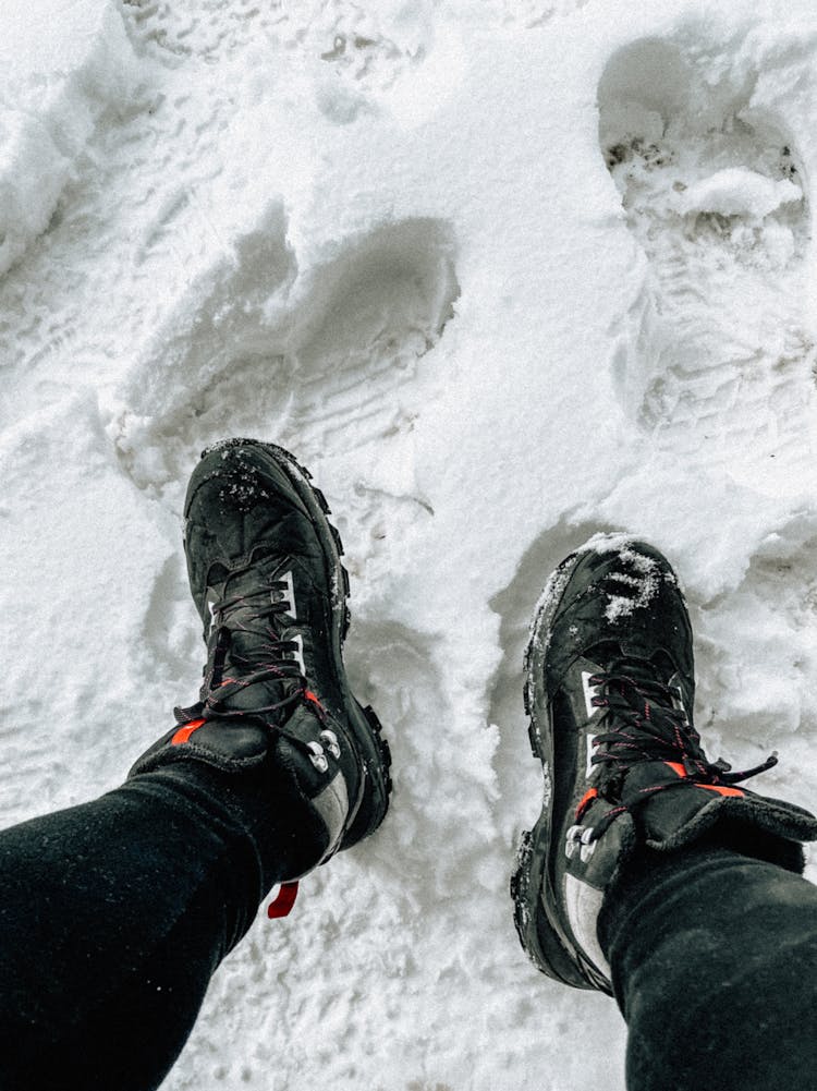 A Person Wearing A Hiking Shoes While Stepping On The Snow