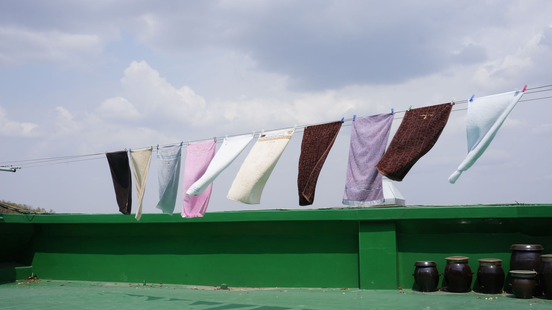 Vibrant towels hanging on a clothesline against a clear sky, perfect for homely and lifestyle themes.