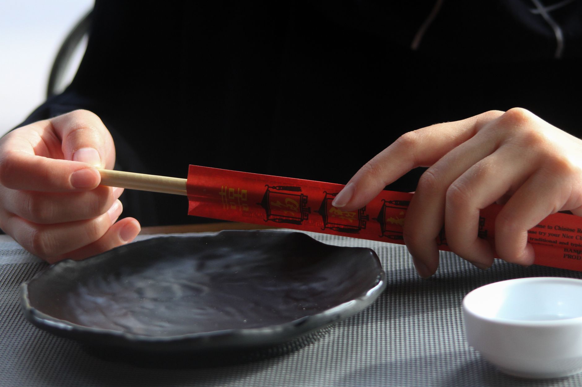 Close-up shot of hands holding chopsticks over an empty plate, perfect for Asian cuisine themes.
