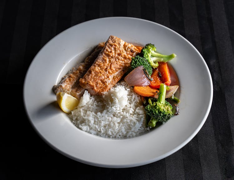 A Salmon With Stir Fry Vegetables And Rice On The Side