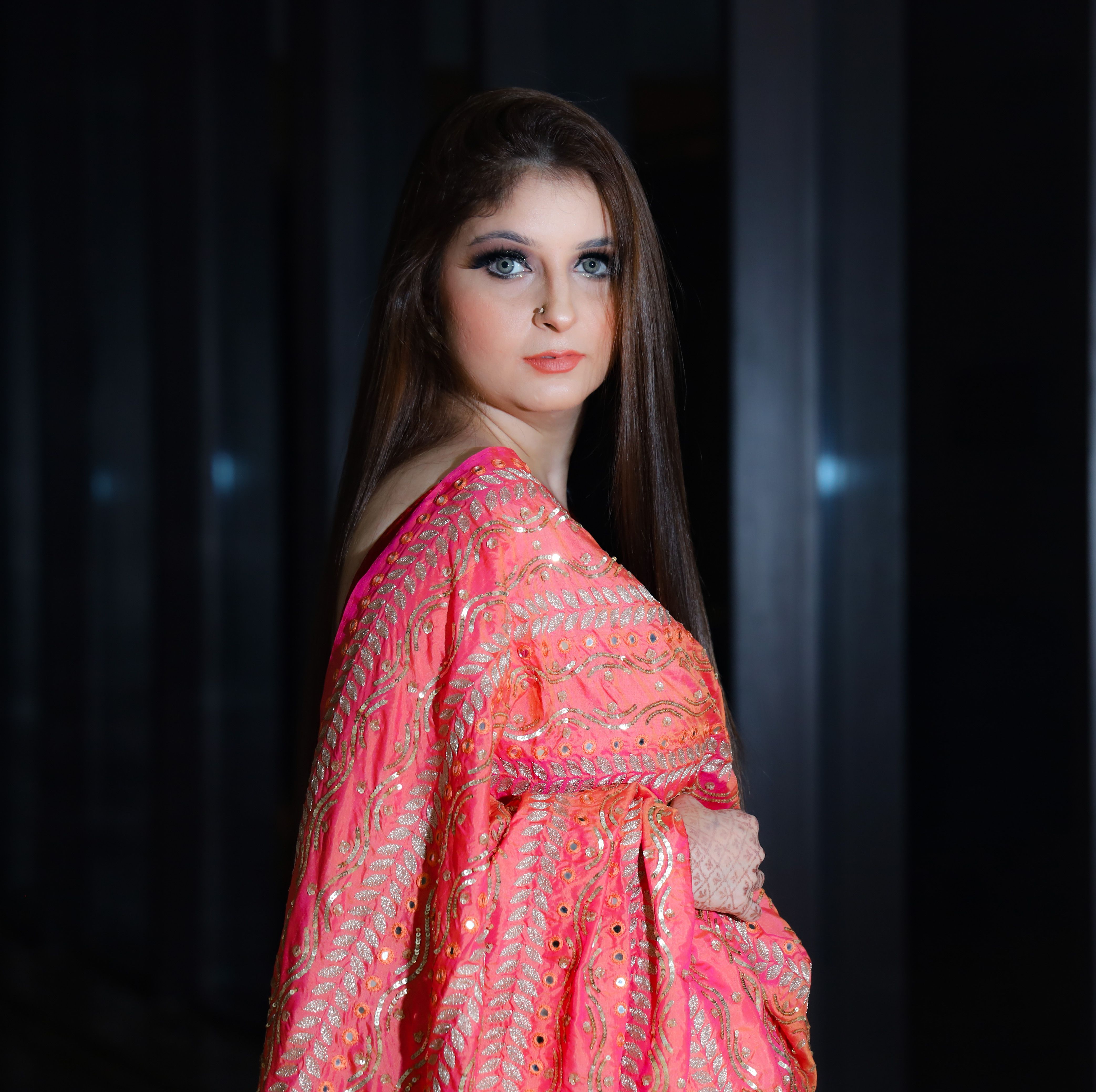 Portrait of a young woman in an embroidered pink traditional gown, exuding elegance and grace.