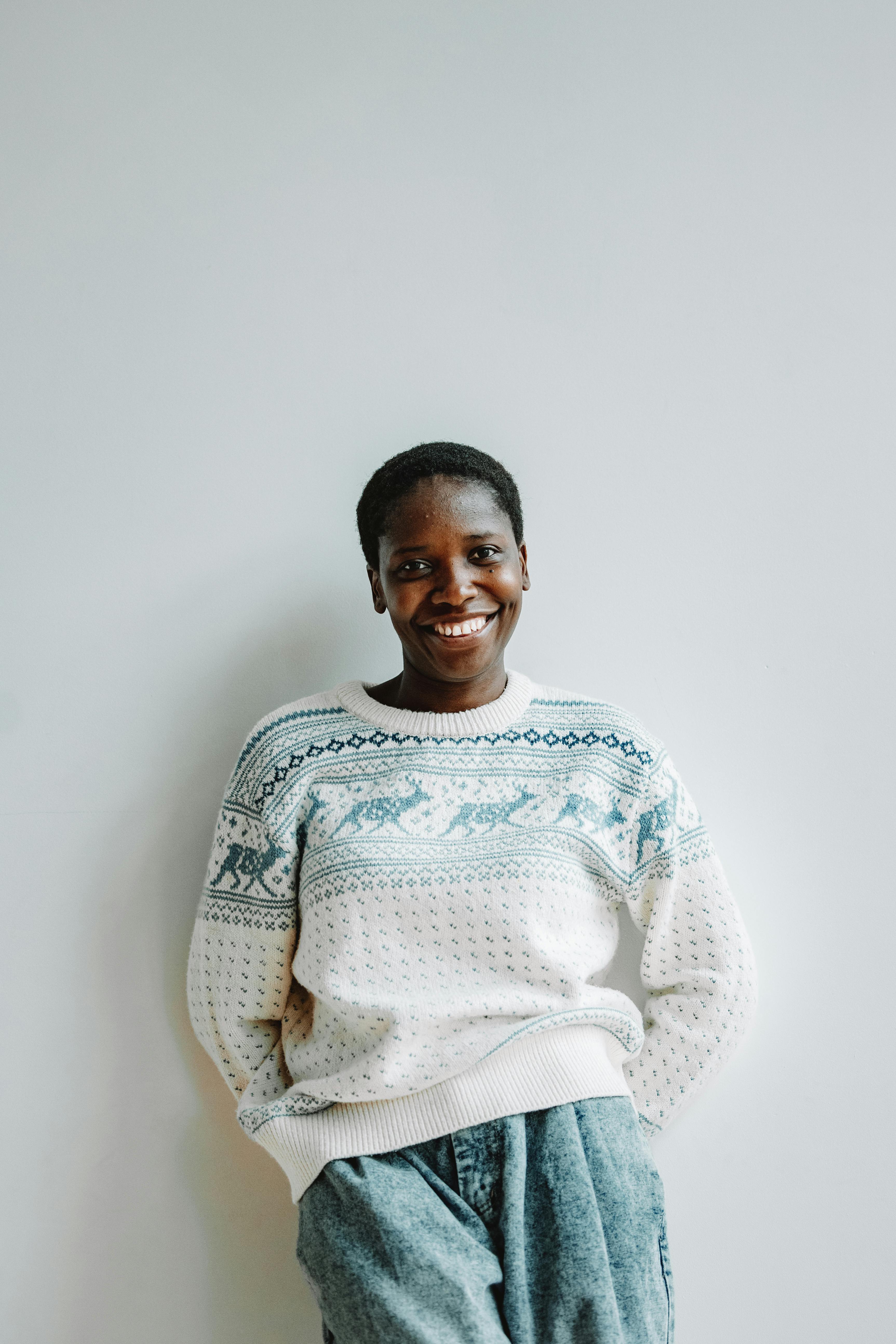 a woman in ugly christmas sweater standing beside a wall