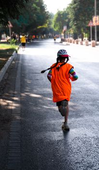 A young girl in colorful attire runs in an urban marathon, showcasing energy and determination.