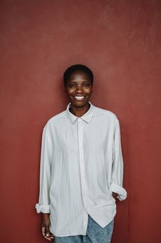 Portrait of a smiling person wearing a white shirt against a red background, exuding warmth and positivity.