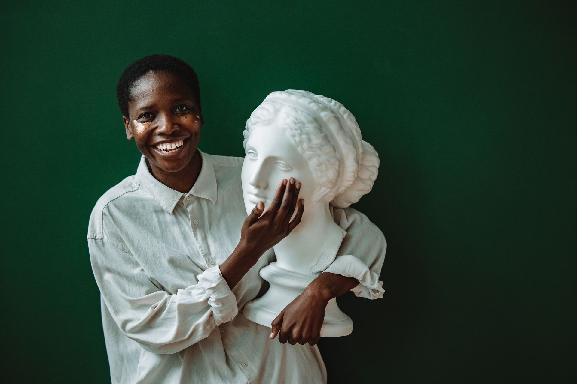 A Woman in White Dress Shirt Holding a Woman Head Bust