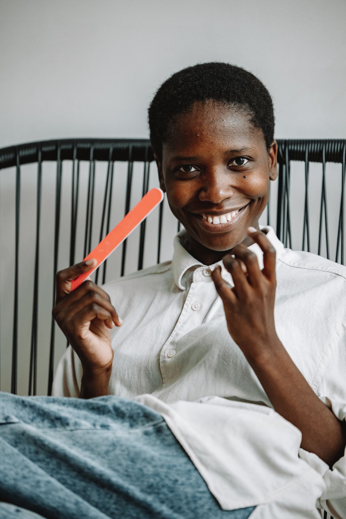 Happy woman enjoying manicure while sitting indoors. Relaxed and cheerful atmosphere.