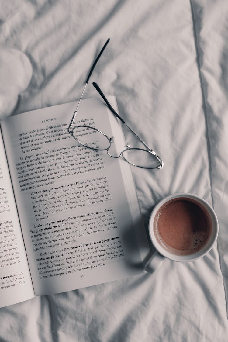 Eyeglasses On Book And Coffee On Linen