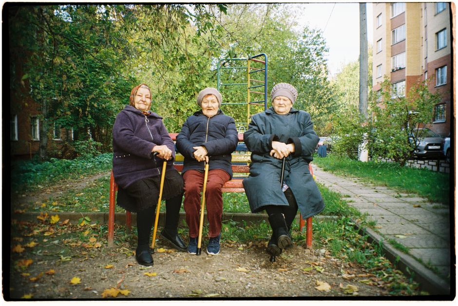 Three senior women with walking sticks sitting on a park bench.
