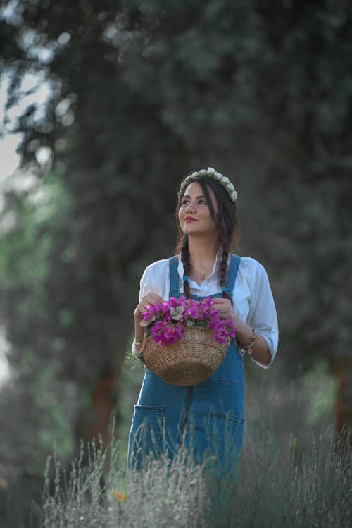 Smiling Girl Carrying a Basket of Pink Flowers