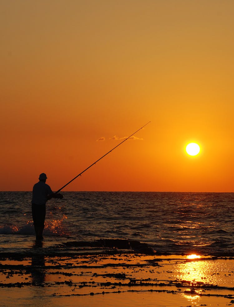 Silhouette Of A Man Fishing At The Beach