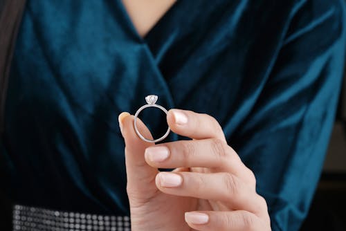 Person Holding Silver Ring on Left Hand