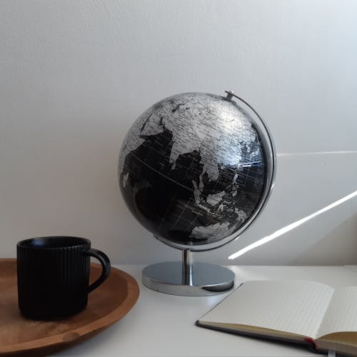 Black Ceramic Mug Beside Desk Globe