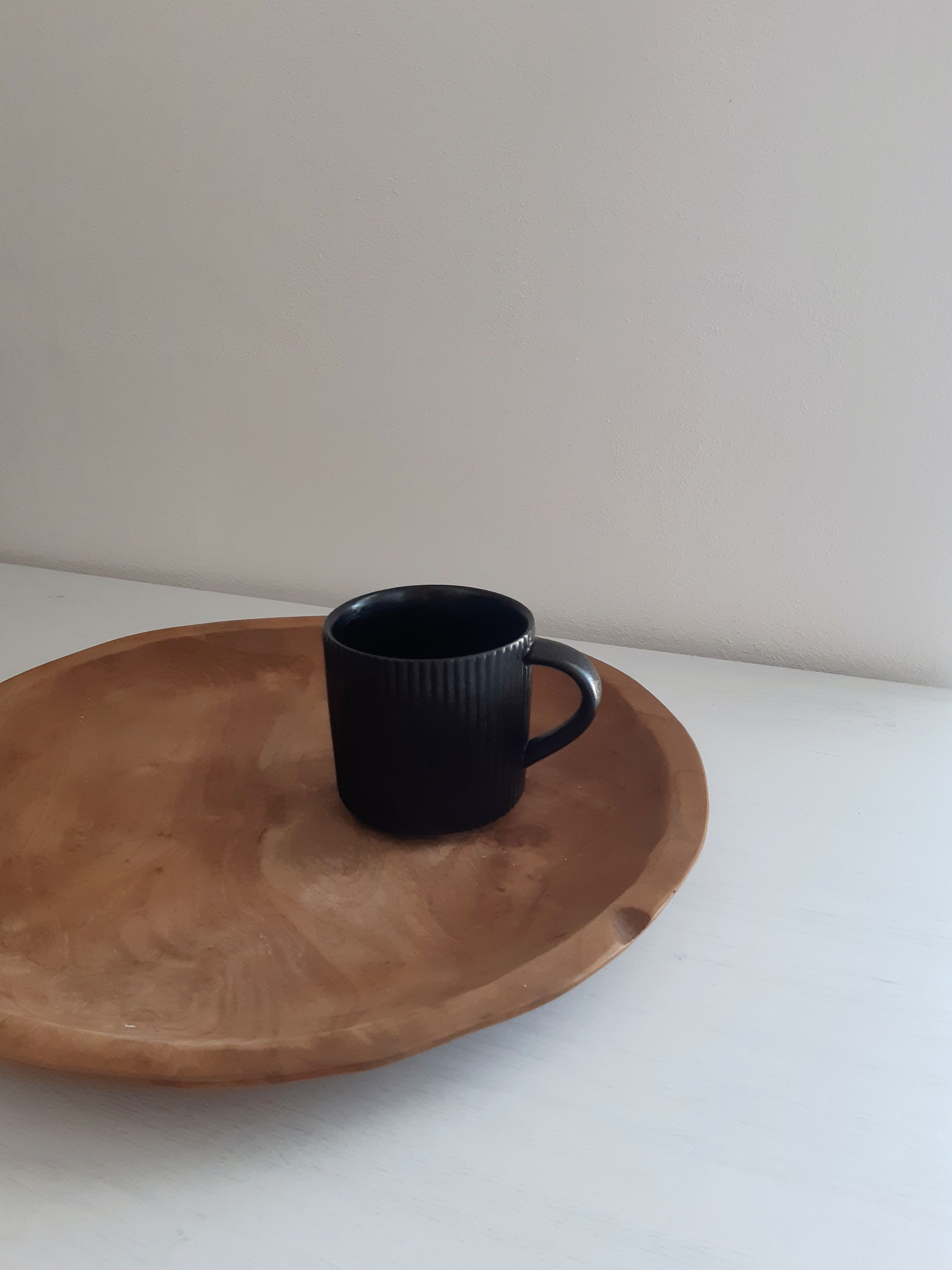 Sleek matte black mug rack holding assorted mugs on a modern coffee and tea bar