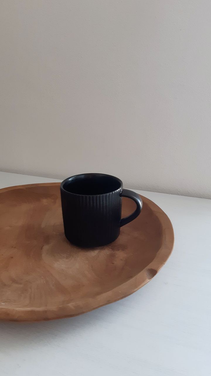 Sleek matte black mug rack holding assorted mugs on a modern coffee and tea bar