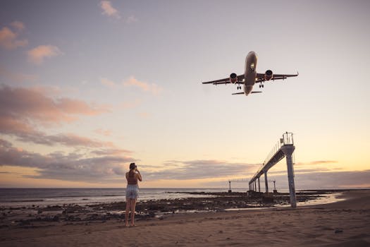 A woman captures a plane landing at a scenic Lanzarote beach during sunset.