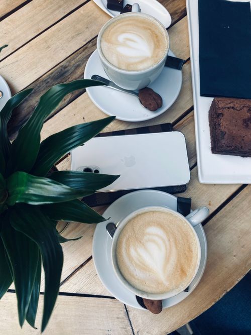 Free Overhead view of coffee, brownie, and smartphone on a wooden table, perfect for a cozy café scene. Stock Photo